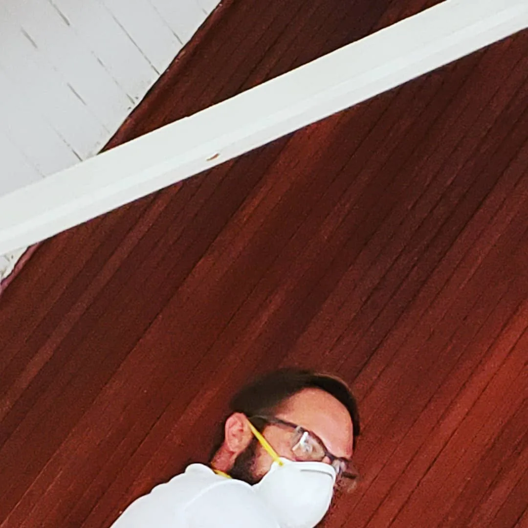 Masked field worker inspecting an interior ceiling area