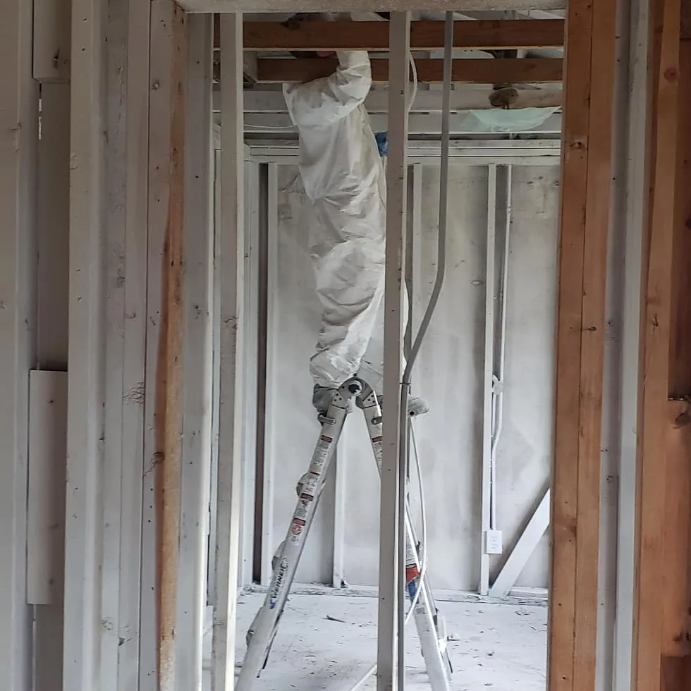 Worker in protective clothing inside an opened wall and ceiling work area